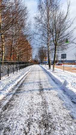 The path is cleaned from the snow, in winter the snow is cleared on the asphalt in the city. A cleared road for passers-by.の写真素材