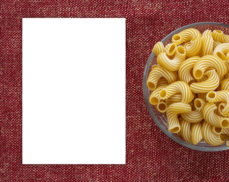 cavatappi pasta in a wooden bowl on a red brown cloth burlap background with a side. White space for...