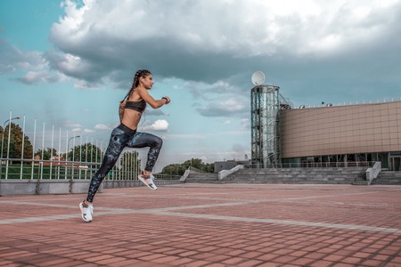 Beautiful jumping girl froze air. Active lifestyle, jogging and running city summer fresh air. Concept of strength, endurance, slim figure. Sport muscles in motion. Free space for text motivation.の写真素材