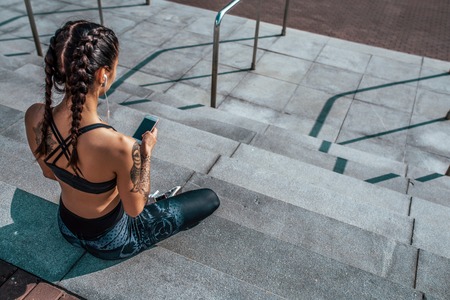 Woman athlete in tattoos, in summer city, resting after workout fitness, workout. Sportswear...