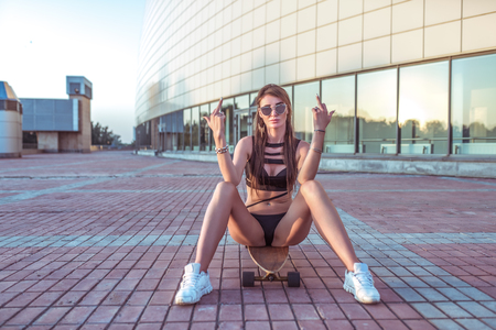 Beautiful young girl summer city, shows middle finger, gesture is no stop, went from here on board. Fashion lifestyle youth. Concept enough, back off, good night, no, not interesting, got out.の写真素材