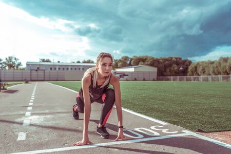 girl on sports circle, summer city on sports ground, stands before start of race, training distance...