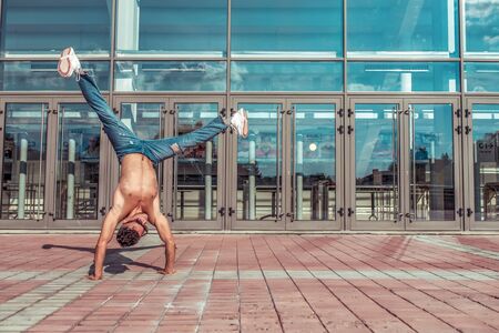 Man athlete, dancer summer. Handstand, free space motivation text. Background glass windows....