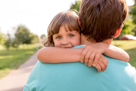 Happy girl 5-7 years old, hugs a man dad, in summer in a city park, emotion of joy, fun, relaxation and enjoyment. Dads day. Happy family conceptの写真素材