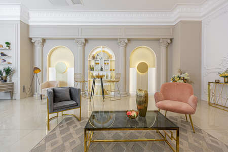 chic luxury interior in an old antique style open-plan apartment decorated with columns and stucco on the wall in pastel colors. tiles on the floor. beige wallsの写真素材