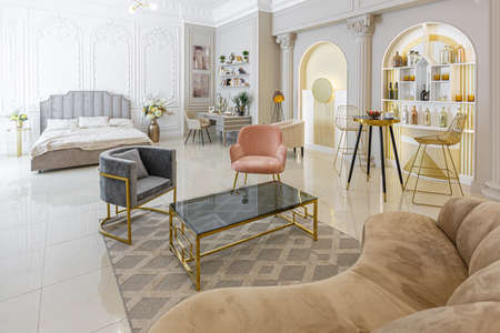 chic luxury interior in an old antique style open-plan apartment decorated with columns and stucco on the wall in pastel colors. tiles on the floor. beige wallsの写真素材