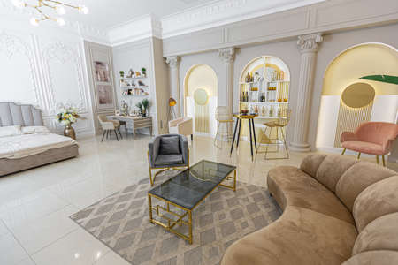 chic luxury interior in an old antique style open-plan apartment decorated with columns and stucco on the wall in pastel colors. tiles on the floor. beige wallsの写真素材
