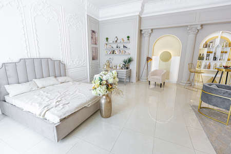 chic luxury interior in an old antique style open-plan apartment decorated with columns and stucco on the wall in pastel colors. tiles on the floor. beige wallsの写真素材