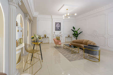 chic luxury interior in an old antique style open-plan apartment decorated with columns and stucco on the wall in pastel colors. tiles on the floor. beige wallsの写真素材