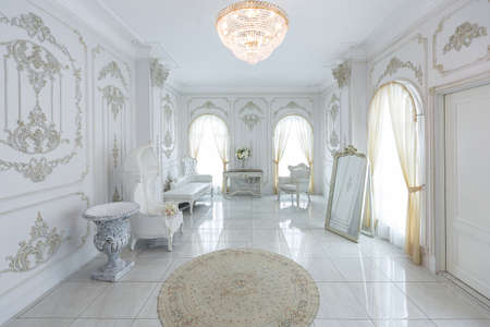 luxury royal posh interior in baroque style. very bright, light and white hall with expensive oldstyle furniture. large windows and stucco ornament decorations on the wallsの写真素材
