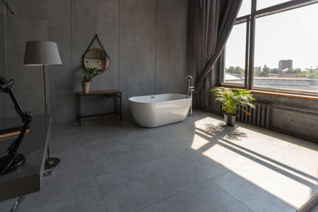 Modern minimalistic dark gray loft style studio apartment interior design. kitchen, sitting area, workplace, shower and bath. bright sun rays inside.の写真素材