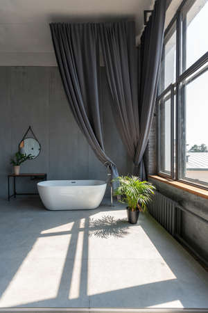 Modern minimalistic dark gray loft style studio apartment interior design. kitchen, sitting area, workplace, shower and bath. bright sun rays inside.の写真素材