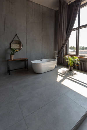Modern minimalistic dark gray loft style studio apartment interior design. kitchen, sitting area, workplace, shower and bath. bright sun rays inside.の写真素材