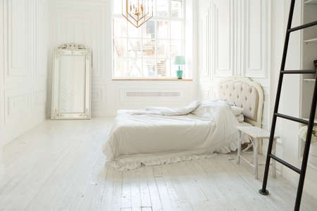 Stylish luxury white bedroom interior design in soft day light with elegant classic furnitureの写真素材