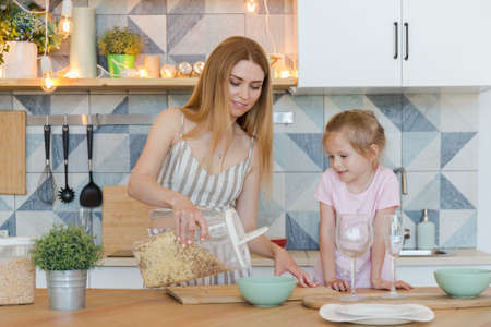 beautiful blonde mother and cute little daughter having fun and playing in fashionable flat with a...