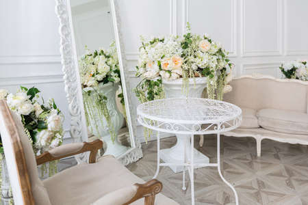 Luxury white interior of living spacious room with elegant chic furniture and high windows.