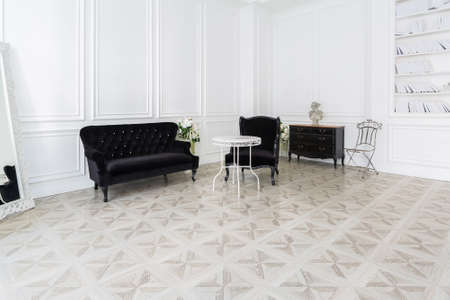 Luxury white interior of living spacious room with elegant chic furniture and high windows.