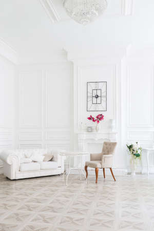 Luxury white interior of living spacious room with elegant chic furniture and high windows.の写真素材