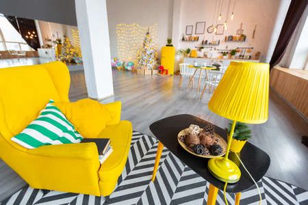 Trendy fashion luxury interior design in Scandinavian style of studio apartment with bright yellow furniture and decorated with new year lights.の写真素材