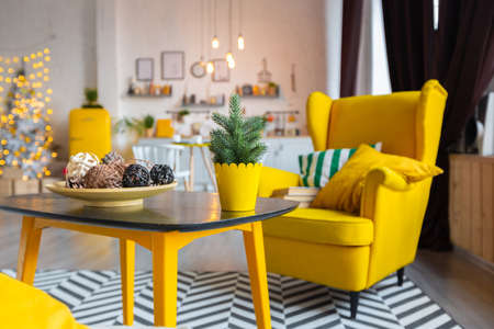 Trendy fashion luxury interior design in Scandinavian style of studio apartment with bright yellow furniture and decorated with new year lights.の写真素材