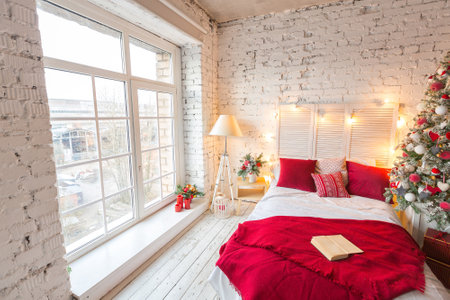 A spacious white light bedroom in a loft style with a decorated Christmas tree and a garland.の写真素材