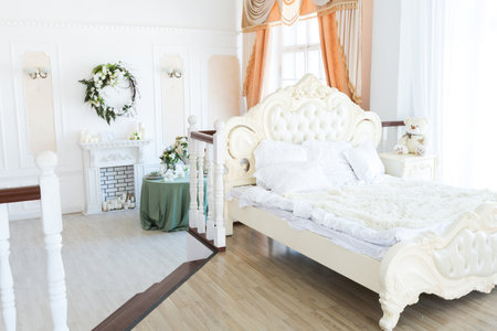 Luxury stylish bright light interior of sitting room. White walls decorated by ornament. Fireplace. Nobody inside room. Table setting by dishes, candles and flower bouquets.の写真素材