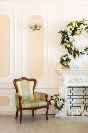 Luxury stylish bright light interior of sitting room. White walls decorated by ornament. Fireplace. Nobody inside room. Table setting by dishes, candles and flower bouquets.の写真素材