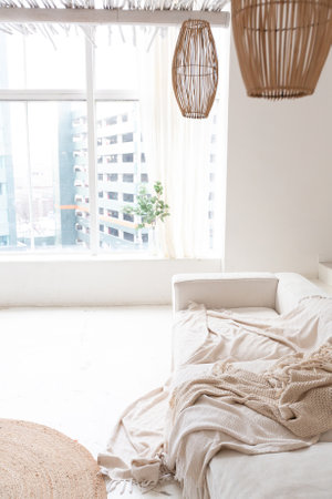 Cozy interior of a bright Balinese-style apartment with white walls, bamboo chair, big white sofa and decorationsの写真素材