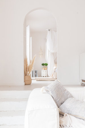 Cozy interior of a bright Balinese-style apartment with white walls, bamboo chair, big white sofa and decorationsの写真素材