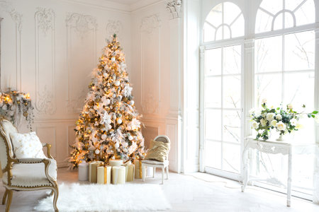 luxurious expensive light interior living room in a royal style decorated with a very beautiful Christmas tree and large windowsの写真素材
