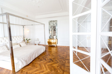 modern interior of a luxurious large bright bedroom. white stucco walls and a large four-poster bed and wooden parquet floorの写真素材