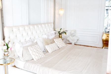 modern interior of a luxurious large bright bedroom. white stucco walls and a large four-poster bed and wooden parquet floorの写真素材