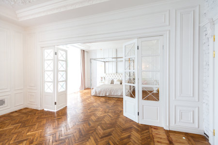 modern interior of a luxurious large bright bedroom. white stucco walls and a large four-poster bed and wooden parquet floorの写真素材