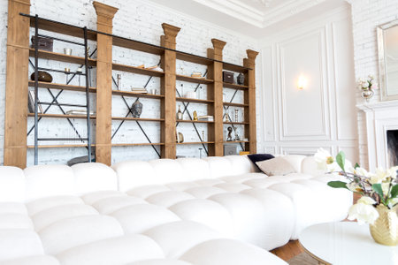 modern interior of a luxurious large bright living room. white expensive sofa and wooden shelving,...