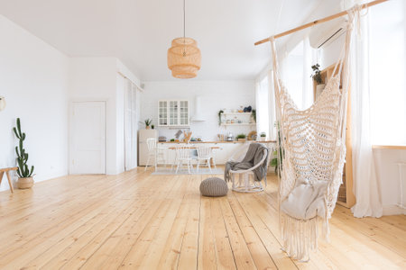 cute cozy light interior design of the apartment with a free layout of the kitchen and bedroom areas. a lot of windows, a wooden floor and a hanging swing.の写真素材