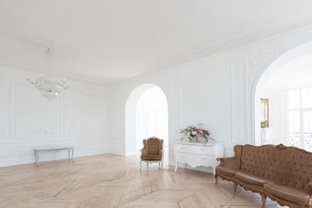 chic white huge spacious hall with a minimum of expensive antique furniture. Baroque interior design with ornament on the walls and parquet on the floor.の写真素材