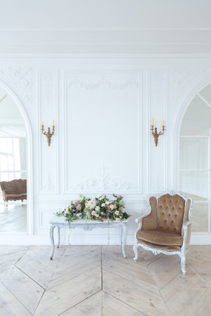 chic white huge spacious hall with a minimum of expensive antique furniture. Baroque interior design with ornament on the walls and parquet on the floor.の写真素材