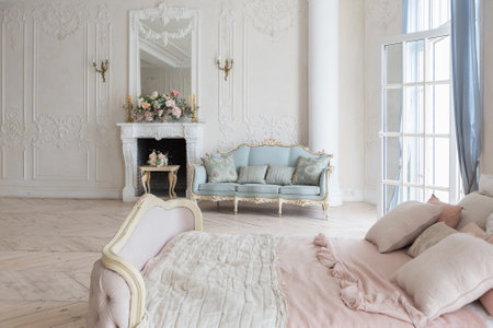 luxurious light interior in the Baroque style. A spacious room with a road chic beautiful furniture, a fireplace and flowers. plant stucco on the walls and light wood parquetの写真素材