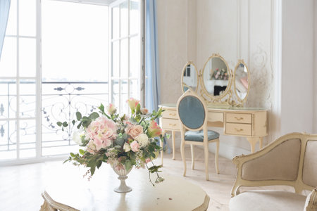 luxurious light interior in the Baroque style. A spacious room with a road chic beautiful furniture, a fireplace and flowers. plant stucco on the walls and light wood parquetの写真素材