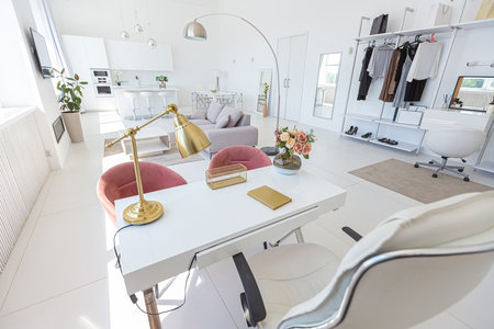 Cozy luxury modern interior design of a studio apartment in extra white colors with fashionable expensive furniture in a minimalist style. white tiled floor, kitchen, relaxation area and workplaceの写真素材