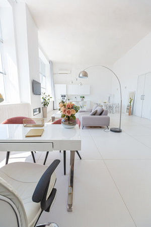 Cozy luxury modern interior design of a studio apartment in extra white colors with fashionable expensive furniture in a minimalist style. white tiled floor, kitchen, relaxation area and workplaceの写真素材