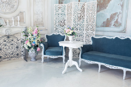 Bright luxury white and blue colored interior living room with flowers in vases. the walls are...