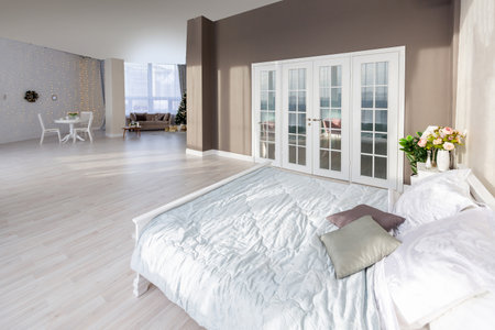 Luxurious and expensive interior of an open-plan apartment in light colors. Stylish modern bedroom with minimal design, dining area and guest space.の写真素材