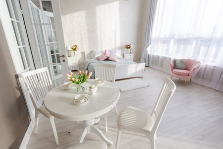 Luxurious and expensive interior of an open-plan apartment in light colors. Stylish modern bedroom with minimal design, dining area and guest space.の写真素材