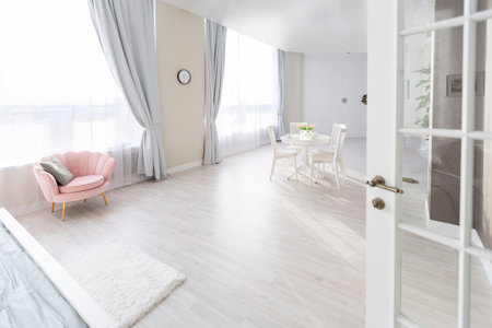 Luxurious and expensive interior of an open-plan apartment in light colors. Stylish modern bedroom with minimal design, dining area and guest space.の写真素材
