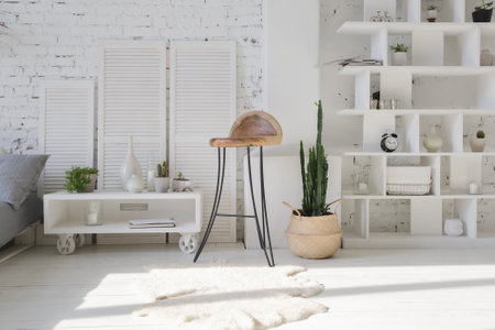 Spacious stylish modern trendy loft apartment in white and light colors. a large room full of sunlight. brick wall, wood floor, shelving, pallet bed and huge window. everything is white with gray tints.の写真素材