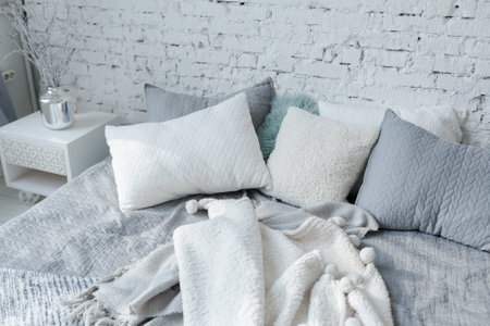 Spacious stylish modern trendy loft apartment in white and light colors. a large room full of sunlight. brick wall, wood floor, shelving, pallet bed and huge window. everything is white with gray tints.の写真素材
