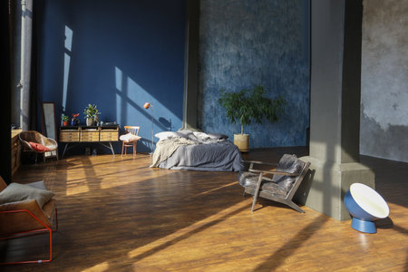 dark interior of a modern stylish huge open-plan loft-style studio apartment with columns and high ceilings. dark blue primed walls are decorated with wood. sunlight enters through huge windows.の写真素材