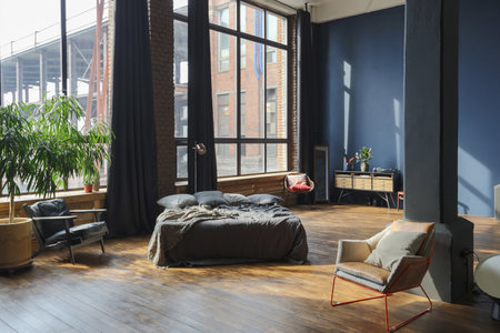 dark interior of a modern stylish huge open-plan loft-style studio apartment with columns and high ceilings. dark blue primed walls are decorated with wood. sunlight enters through huge windows.の写真素材