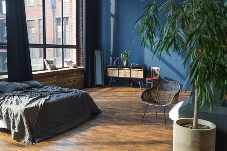 dark interior of a modern stylish huge open-plan loft-style studio apartment with columns and high ceilings. dark blue primed walls are decorated with wood. sunlight enters through huge windows.の写真素材